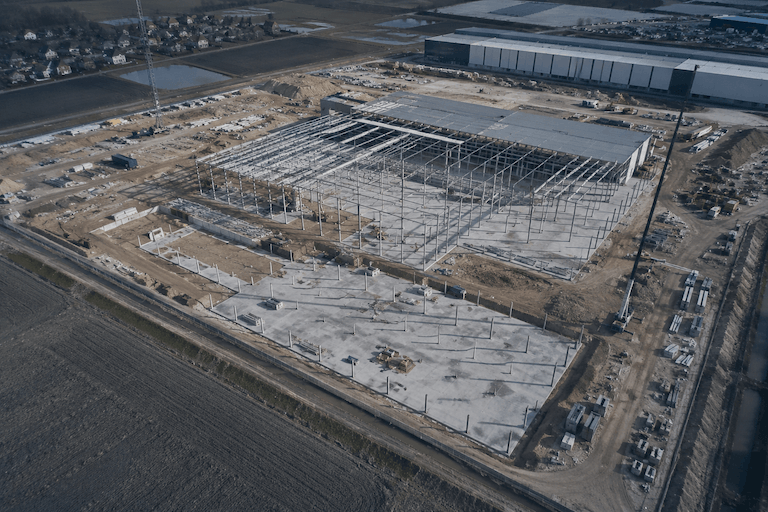 Aerial shot budowy centrum logistycznego - stalowa konstrukcja i fundamenty, widok z drona